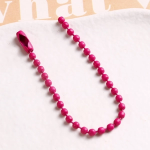Macro shot of rose pink ball chain necklace with metal connector on white tray