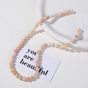 Macro detail of 8mm pastel cracked round stone beads in pink, yellow, and white for DIY