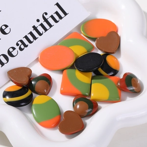 Colorful geometric resin charms in heart and square shapes on a white jewelry tray