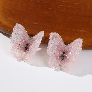 Macro detail of pink butterfly charms with shimmering crystals for DIY jewelry making