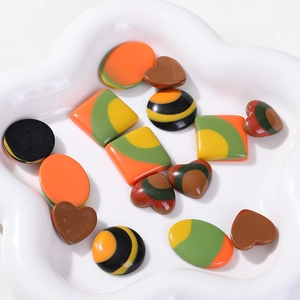 Macro detail of multi-colored geometric resin charms for DIY jewelry in a ceramic dish