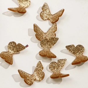 Detail view of golden glitter resin butterfly charms for DIY jewelry and hair accessories