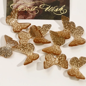 Close-up of golden butterfly resin accessories with sparkling sequins for DIY jewelry