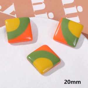 Macro detail of 20mm square resin charms with orange, green, and yellow striped patterns