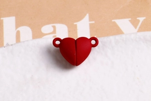 Macro view of a dark red heart-shaped magnetic clasp with a matte finish for DIY jewelry