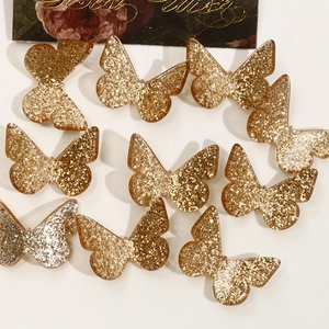 Macro shot of resin butterfly charms with gold sequins for DIY handmade jewelry crafts