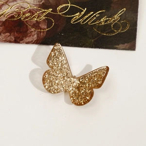 Detail of a golden sequin butterfly accessory with shimmering resin and metallic finish