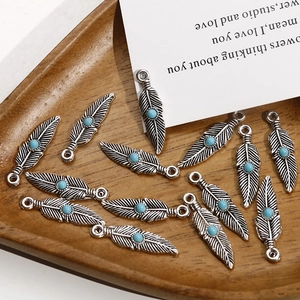 Vue détaillée de breloques plumes en alliage avec pierres turquoise sur plateau bois