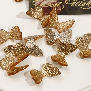 Macro shot of 3D golden glitter resin butterfly charms for DIY craft jewelry making