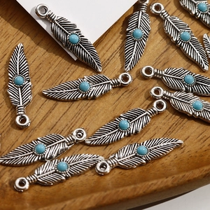 Détail de pendentifs plumes vintage avec perles turquoise pour la création de bijoux