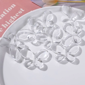 Pendentifs papillons en acrylique transparent pour bijoux DIY sur plateau blanc