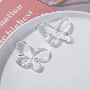 Gros plan de deux pendentifs papillons en acrylique transparent sur un plateau blanc