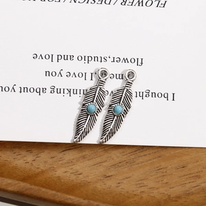 Gros plan sur des pendentifs plume en argent antique avec perles turquoise détaillées