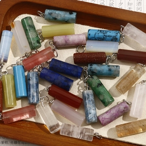 Macro view of natural stone cylinder pendants in wooden tray for DIY jewelry making