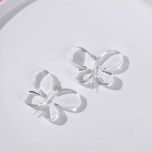 Vue détaillée des pendentifs papillons en acrylique transparent avec anneaux dorés pour bijoux
