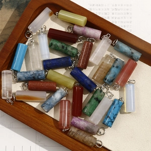 Flat lay of mixed cylinder gemstone pendants with silver hooks for jewelry making