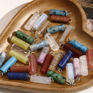 Mix of cylindrical gemstone pendants with silver hooks in a heart-shaped wooden bowl