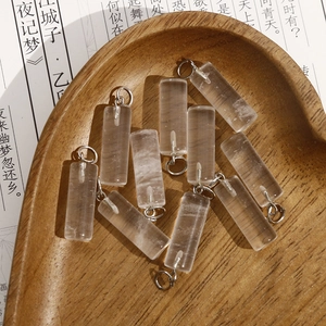 Macro view of rectangular clear crystal pendants with silver loops on a heart wooden tray