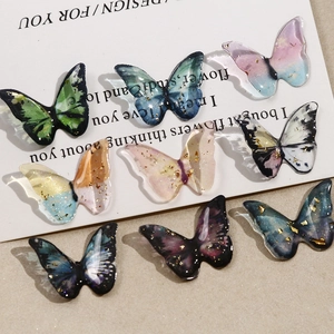 Detailed macro view of resin butterfly charms with gold leaf foil and gradient colors