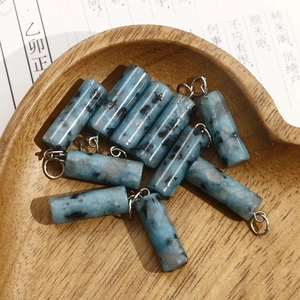 Macro shot of blue spotted natural stone cylinder pendants in a wooden heart-shaped tray