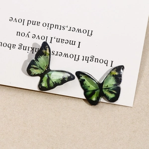 Macro view of handmade green and black resin butterfly charms with gold glitter details