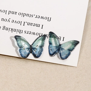 Macro view of blue-green gradient butterfly resin pendant with delicate gold foil flakes