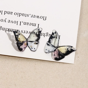 Macro detail of resin butterfly charms with gold foil and colorful ink textures