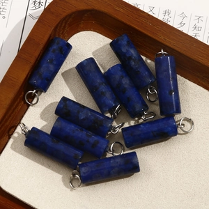 Detail of blue natural stone column pendants with silver rings on a wooden tray