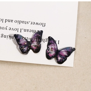 Detail shot of blue and purple resin butterfly charms with gold flakes and starry texture
