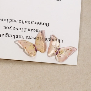 Macro shot of gradient pink and yellow resin butterfly pendant with gold leaf flakes