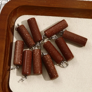 Macro detail of red goldstone cylinder pendants with silver bail on a neutral display