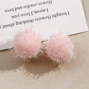 Detailed close-up of pink plush pompoms with iridescent tinsel for DIY jewelry making