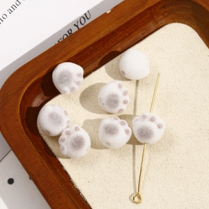 Close-up of DIY flocked cat paw beads with grey paw prints and central drilling detail