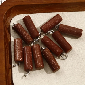 Detailed view of cylindrical goldstone pendants with sparkling flecks and silver metal loops