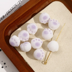 Detail of 10 white and purple cat paw resin beads with gold pin on beige textured pad