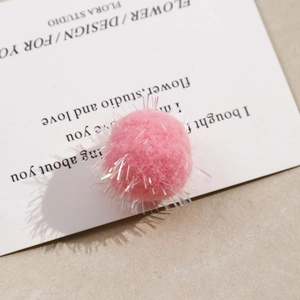 Macro detail of pink plush pom-pom with colorful glitter threads for DIY craft jewelry