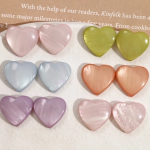 Flat lay of heart-shaped pearlescent resin charms in six pastel colors for DIY jewelry