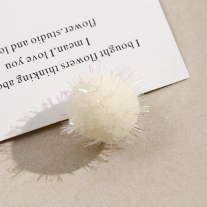 Detail of cream plush pompom with iridescent laser tinsel for DIY jewelry making