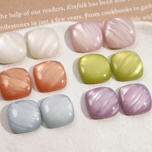 Detailed macro view of colorful pearlescent square resin charms on a textured tray