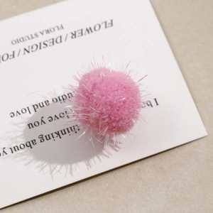 Close-up of pink fluffy pompom with iridescent threads for DIY jewelry making