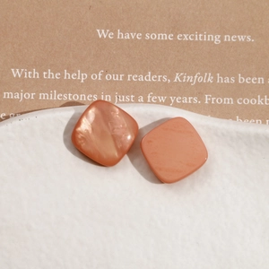 Detailed view of peach resin square stud earrings with mother of pearl texture