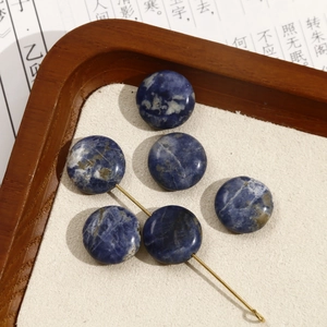 Macro detail van ronde blauwe natuursteen kralen met gouden metalen sieraden pin