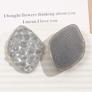 Macro shot of gray diamond resin charms with bubble and frosted textures on ceramic plate