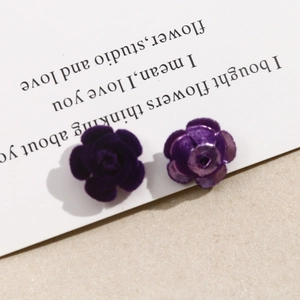 Primer plano de pendientes de rosa de terciopelo morado oscuro en tarjeta blanca
