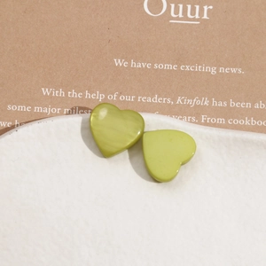 Macro shot of green pearlescent heart resin charms on a white ceramic plate