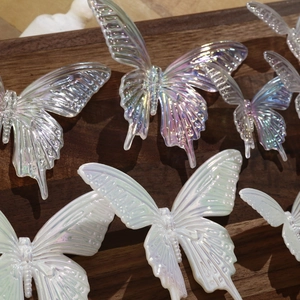 Iridescent resin butterfly charms with Aurora laser effect on dark wood background