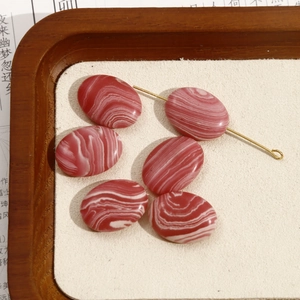 Detail van zes ovale rood-wit gestreepte edelsteenkralen voor het maken van sieraden