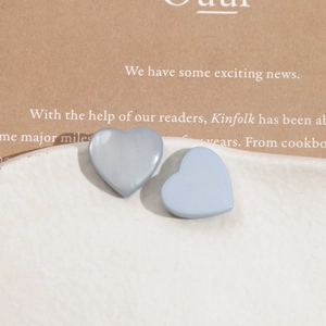 Elegant grey-blue matte resin heart earrings on a white porcelain dish and kraft paper