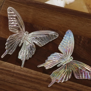 Macro detail of 3D iridescent butterfly accessories with holographic finish on wood