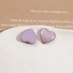 Detail of purple resin heart earrings with pearlescent texture on a ceramic tray
